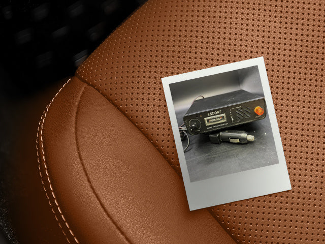 polaroid photo of escort radar detector on leather car seat