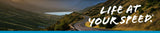 Life at your speed tagline banner over mountain road background image
